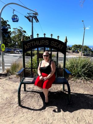 fiona sitting under Arthurs Seat sign with Eagle in background