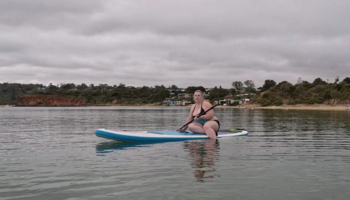 Fiona stand up paddleboarding sitting on board