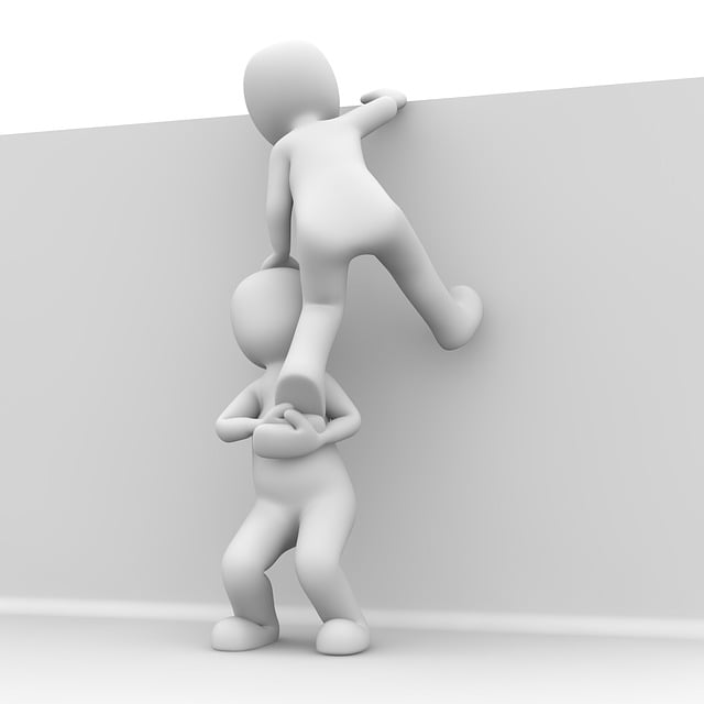 person helping another person climb over a wall